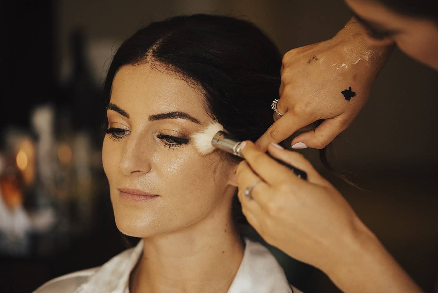 Makeup Artist Applying Highlighter To Bride