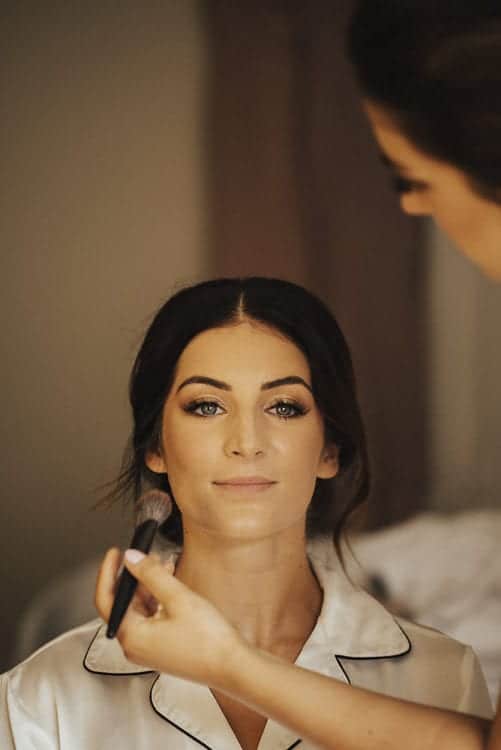 portrait of bride having her makeup applied before wedding ceremony
