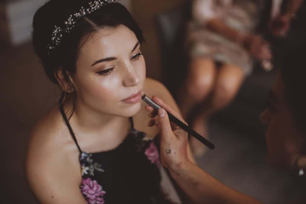 bride with natural glowing makeup having makeup touch ups before wedding ceremony