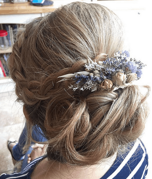 close up of bridal updo with braid and flower hair accessory