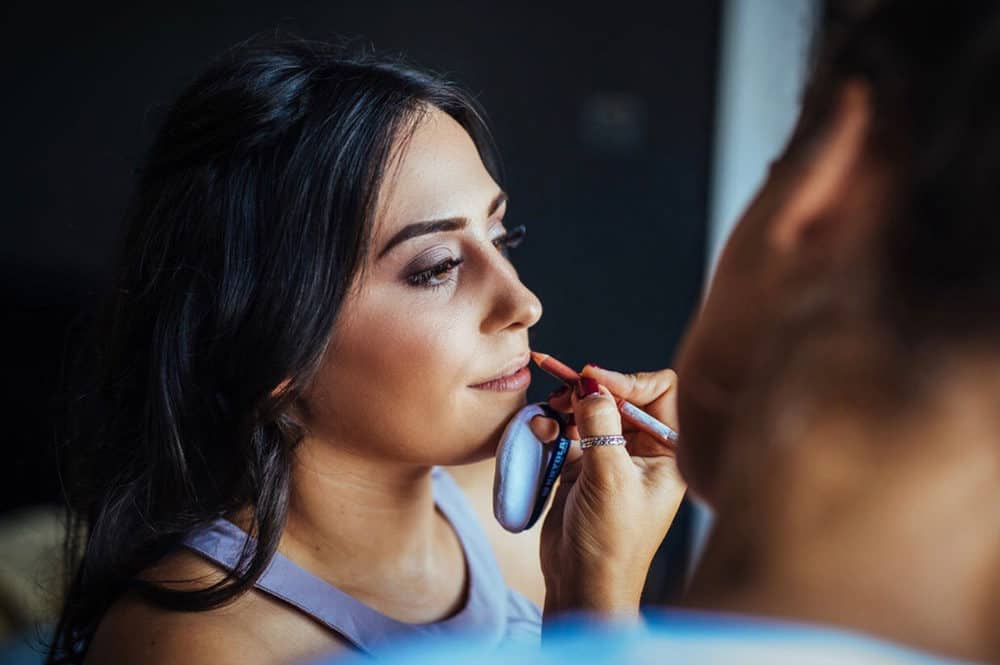 wedding hair and makeup artist Chloe applying lip liner to bridesmaid
