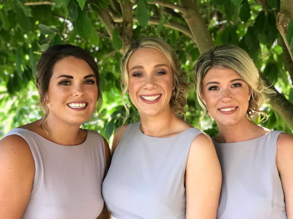 beautiful happy bridesmaids posing by tree